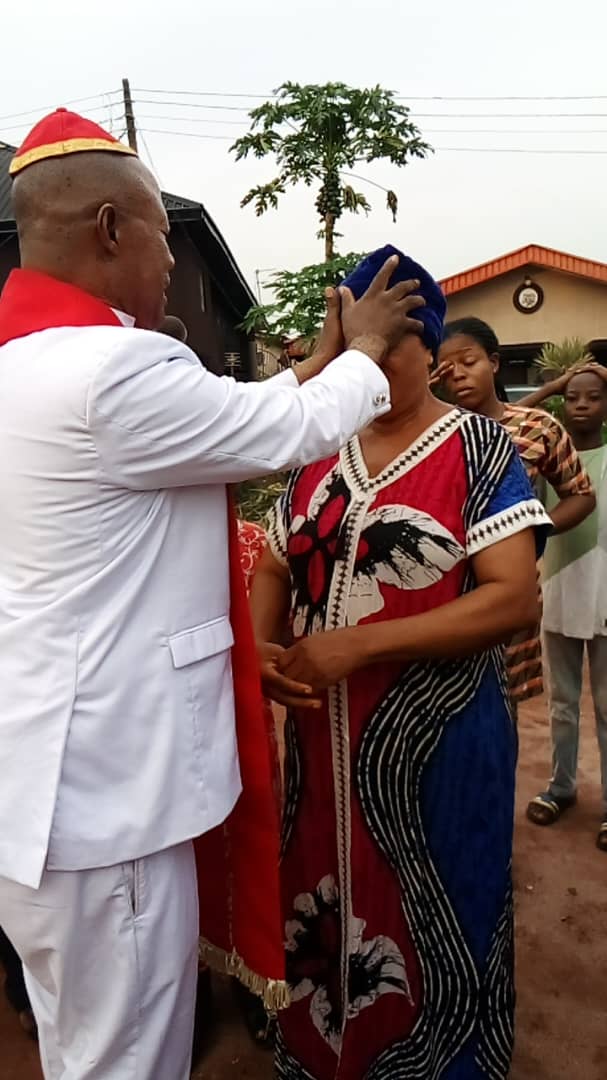 Archbishop Elijah Ayemere Okosun laying hands in prayer over a member of the congregation